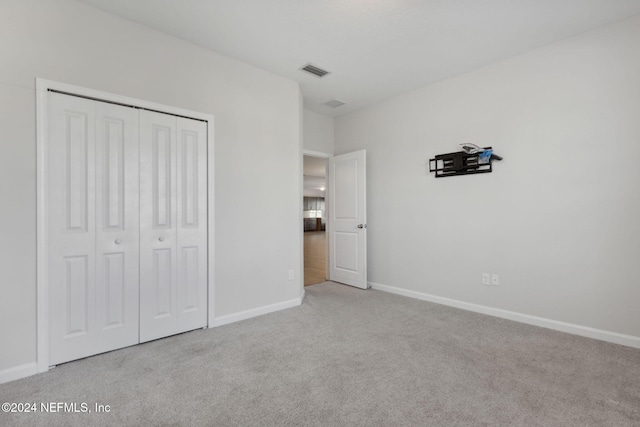 unfurnished bedroom with light carpet and a closet