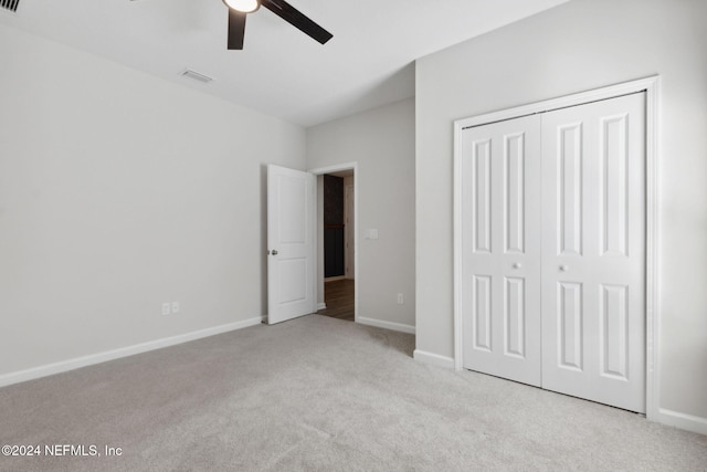 unfurnished bedroom featuring ceiling fan, a closet, and light carpet