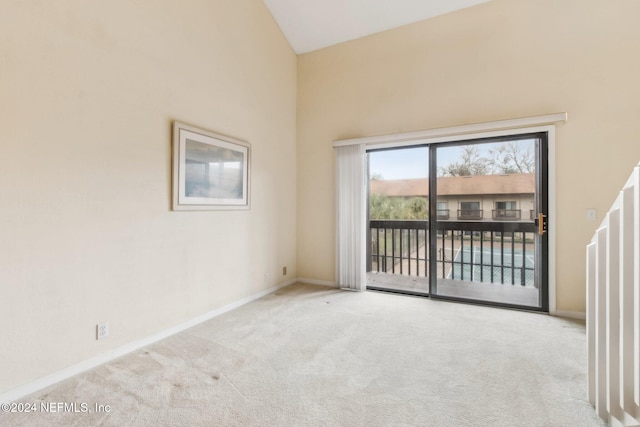 carpeted empty room with high vaulted ceiling