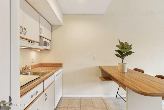 kitchen featuring kitchen peninsula, a kitchen breakfast bar, white appliances, and white cabinetry