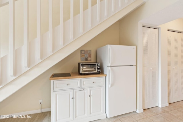 kitchen with white cabinets, white refrigerator, and light tile patterned flooring