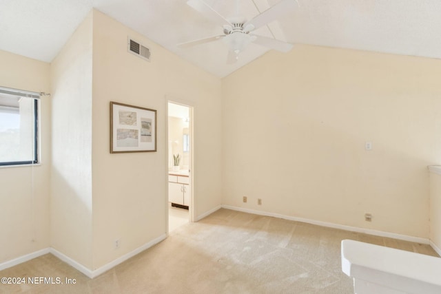 spare room with light carpet, ceiling fan, and vaulted ceiling