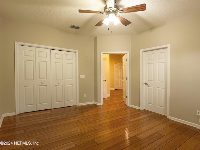 unfurnished bedroom with dark hardwood / wood-style flooring, a textured ceiling, a closet, and ceiling fan