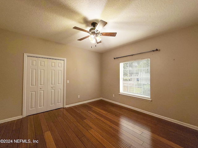 unfurnished bedroom featuring ceiling fan, a closet, dark wood-type flooring, and a textured ceiling