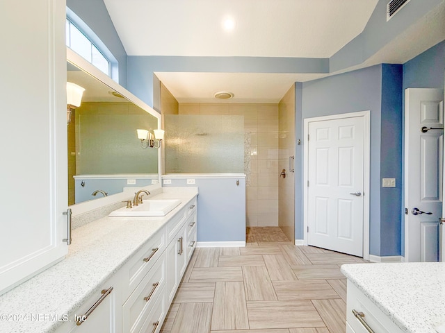 bathroom with a tile shower and vanity