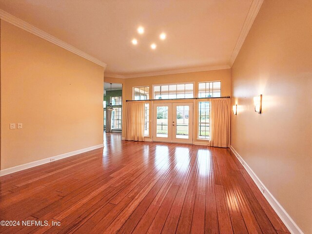 unfurnished living room featuring hardwood / wood-style floors, french doors, and crown molding