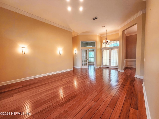 spare room featuring crown molding, french doors, a chandelier, and hardwood / wood-style flooring