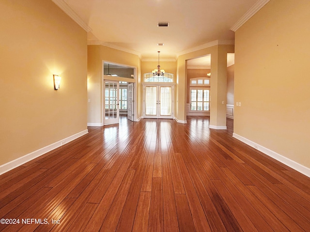 empty room featuring crown molding, french doors, wood-type flooring, and an inviting chandelier