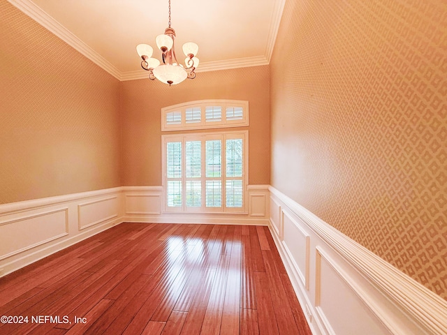 empty room featuring crown molding, wood-type flooring, and an inviting chandelier