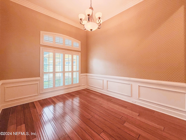 spare room with a chandelier, hardwood / wood-style floors, and ornamental molding