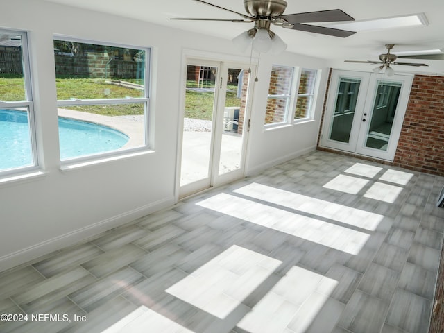 unfurnished sunroom with ceiling fan and french doors