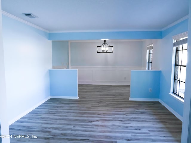 unfurnished dining area featuring dark hardwood / wood-style floors, a healthy amount of sunlight, ornamental molding, and a chandelier