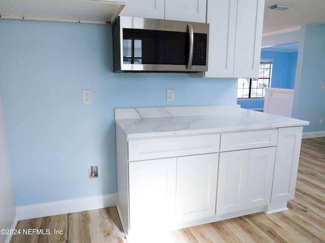 kitchen featuring white cabinets, light stone counters, and light wood-type flooring