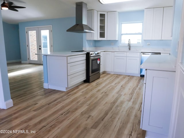 kitchen featuring wall chimney exhaust hood, sink, white cabinetry, and stainless steel appliances