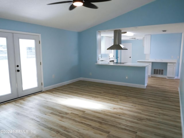 unfurnished living room with ceiling fan, lofted ceiling, light hardwood / wood-style flooring, and french doors