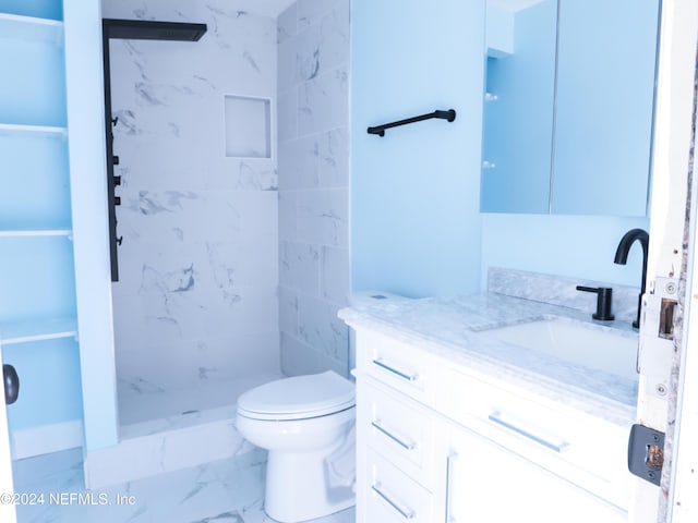 bathroom with vanity, toilet, and a tile shower