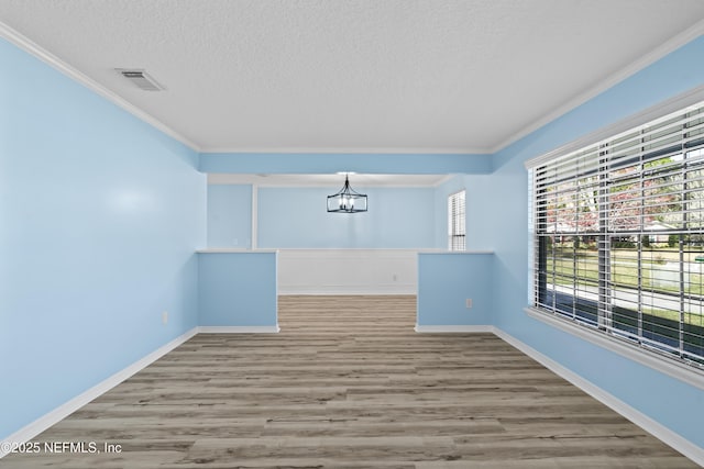 unfurnished room featuring a notable chandelier, ornamental molding, a textured ceiling, and hardwood / wood-style floors