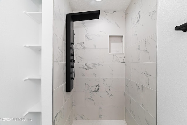 bathroom with a tile shower and a textured ceiling