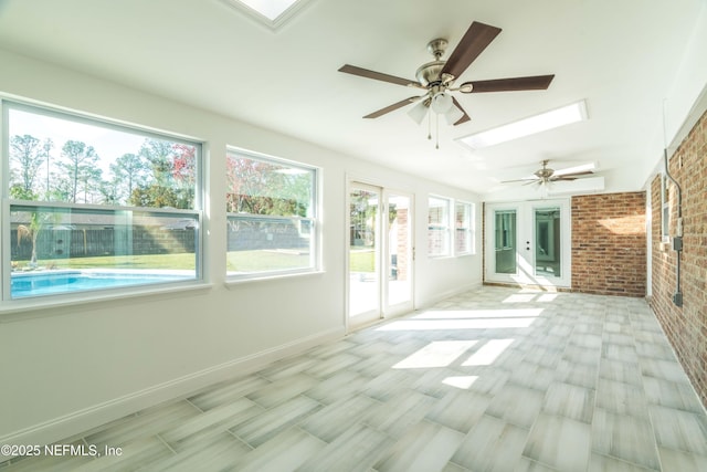 unfurnished sunroom featuring ceiling fan and a skylight