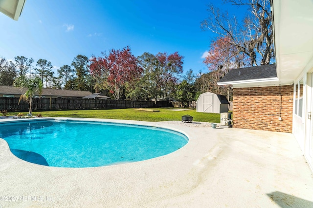 view of swimming pool featuring a storage unit, a fire pit, a lawn, and a patio area