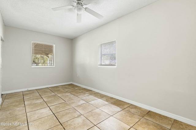 tiled empty room featuring plenty of natural light, ceiling fan, and a textured ceiling