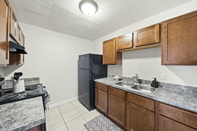 kitchen featuring black refrigerator, light tile patterned floors, range with electric cooktop, and sink