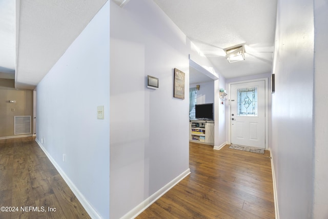 hall featuring a textured ceiling, vaulted ceiling, and dark wood-type flooring