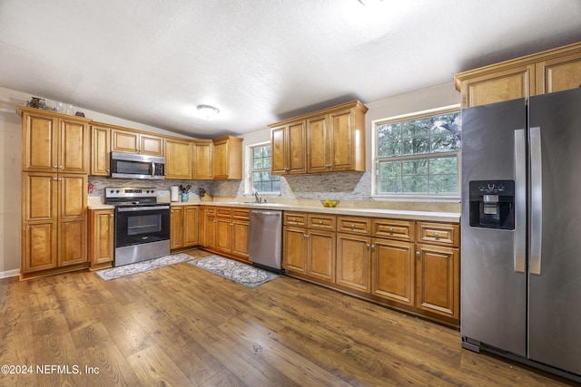 kitchen featuring decorative backsplash, stainless steel appliances, dark wood-type flooring, and sink