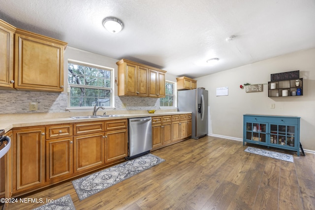 kitchen with dark hardwood / wood-style floors, decorative backsplash, sink, and appliances with stainless steel finishes