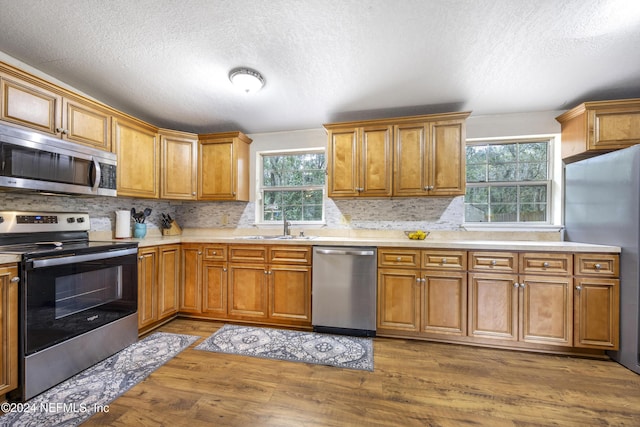 kitchen featuring sink, hardwood / wood-style floors, a textured ceiling, and appliances with stainless steel finishes