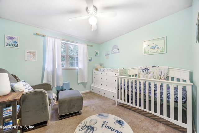 bedroom featuring ceiling fan, light colored carpet, and a crib