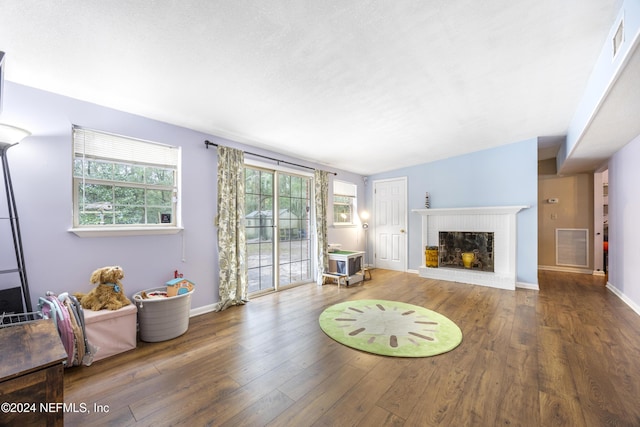 living room featuring a textured ceiling, a fireplace, and dark wood-type flooring