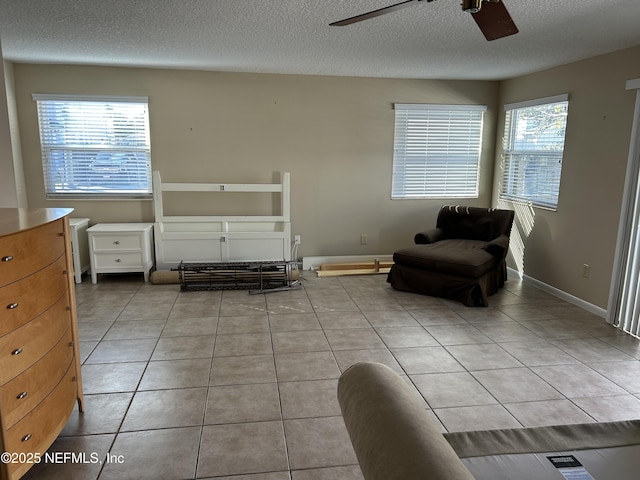 sitting room featuring ceiling fan, a textured ceiling, baseboards, and light tile patterned floors