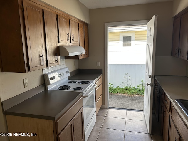 kitchen featuring a wealth of natural light, dark countertops, white electric range oven, and under cabinet range hood