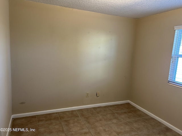 unfurnished room featuring plenty of natural light, baseboards, a textured ceiling, and light tile patterned flooring