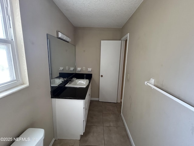 interior space featuring dark countertops, light tile patterned floors, a textured ceiling, and a sink