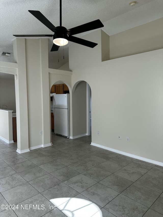 spare room featuring light tile patterned floors, a textured ceiling, high vaulted ceiling, and ceiling fan