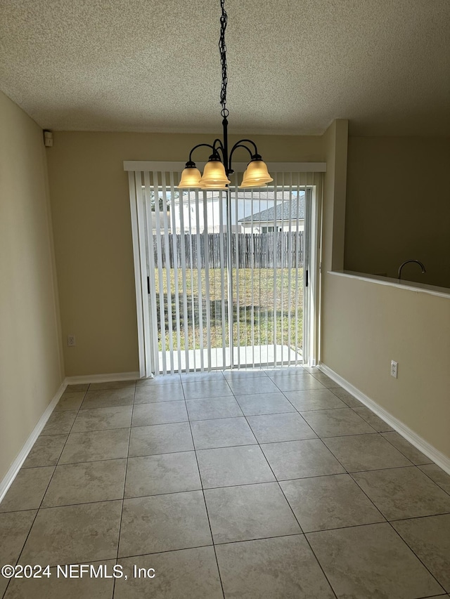 unfurnished dining area featuring light tile patterned flooring, a textured ceiling, and a notable chandelier