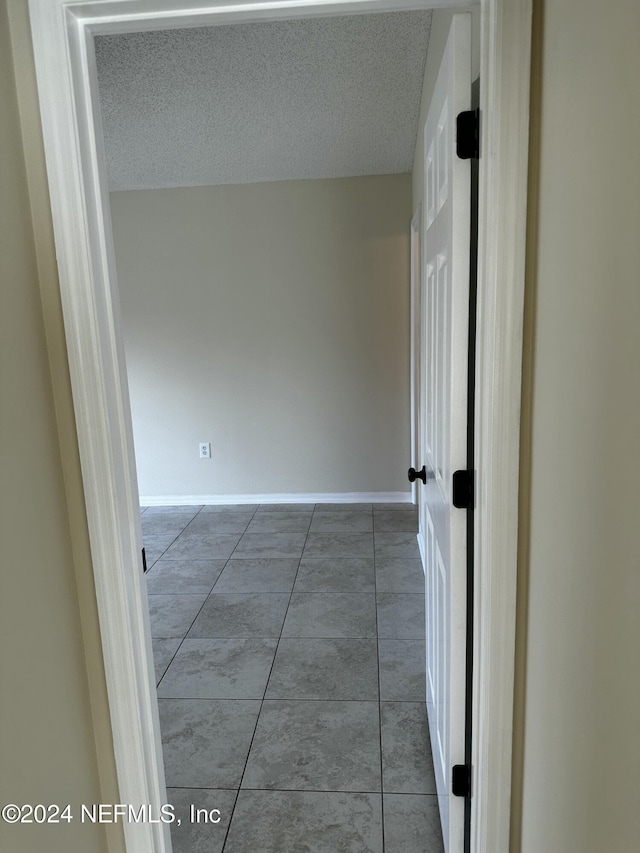 hall featuring a textured ceiling and tile patterned floors