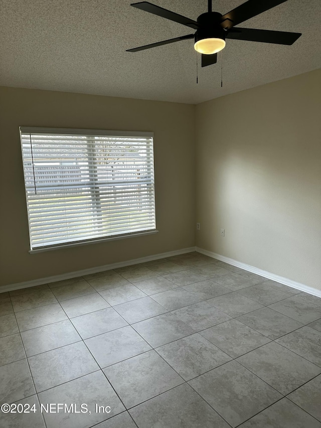 tiled empty room with ceiling fan, a textured ceiling, and a wealth of natural light