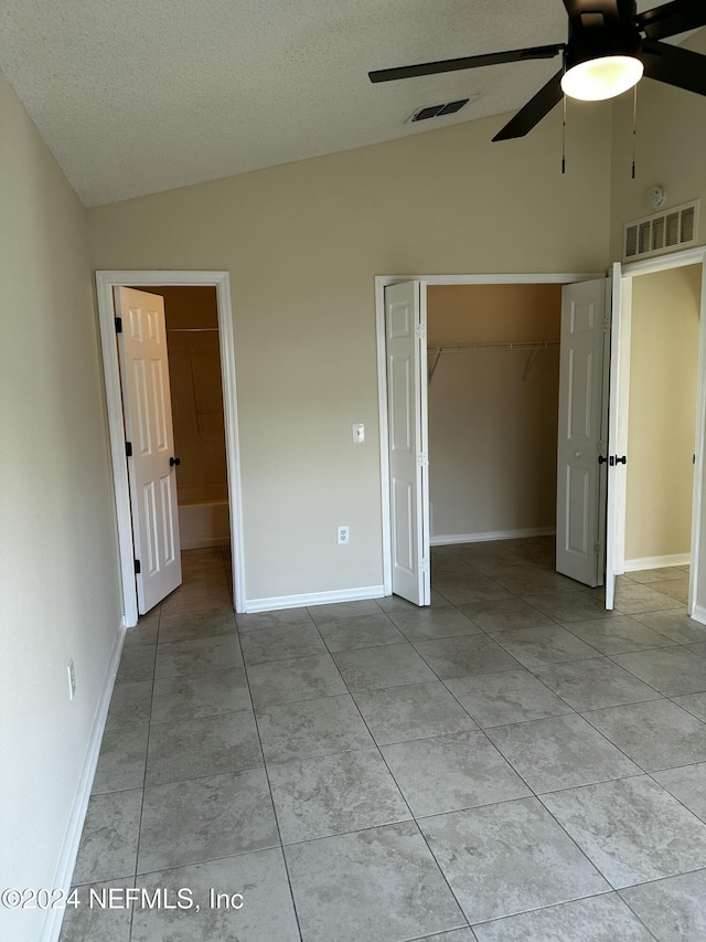 unfurnished bedroom with vaulted ceiling, a closet, a spacious closet, and ceiling fan