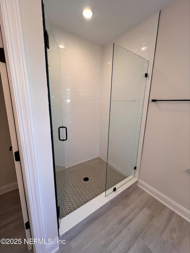 bathroom featuring a shower with door and wood-type flooring