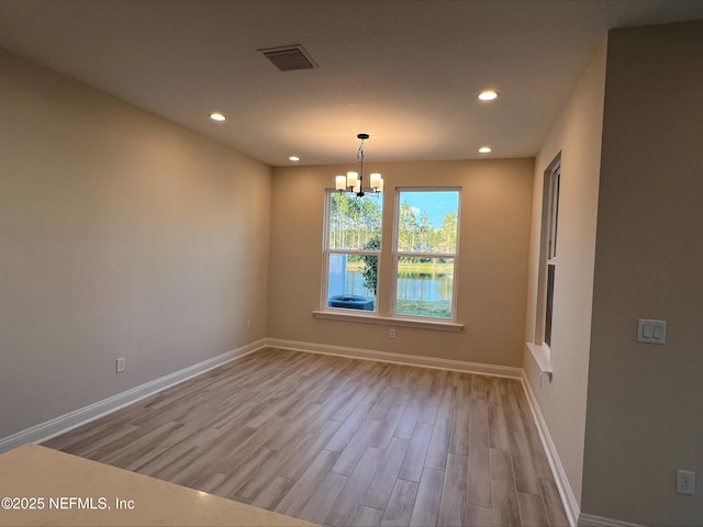 empty room featuring light hardwood / wood-style floors and a notable chandelier