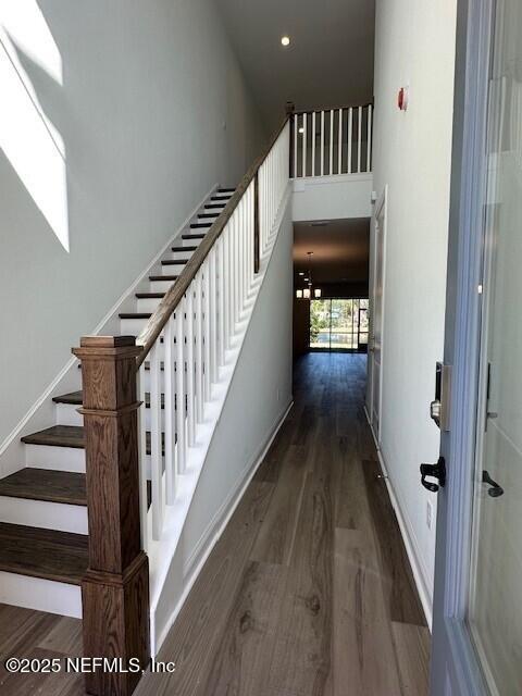 staircase featuring wood-type flooring and a high ceiling