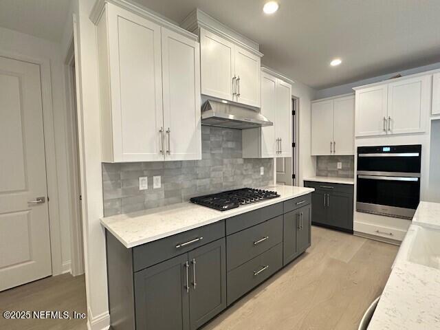 kitchen with gas cooktop, double oven, light hardwood / wood-style flooring, and white cabinets