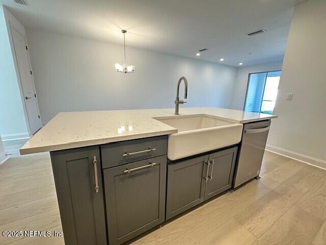 kitchen with sink, hanging light fixtures, light hardwood / wood-style flooring, dishwasher, and an island with sink