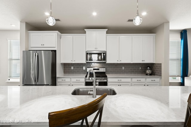 kitchen with white cabinetry, light stone countertops, and stainless steel appliances