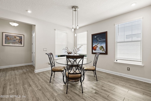 dining space with a textured ceiling and light hardwood / wood-style floors