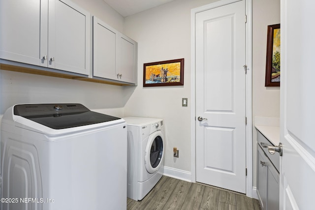 laundry room with washer and clothes dryer, cabinets, and light wood-type flooring