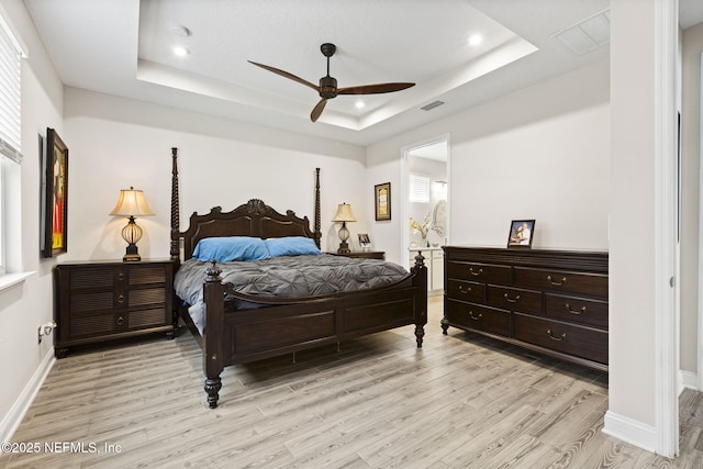 bedroom featuring a tray ceiling, ceiling fan, and light wood-type flooring